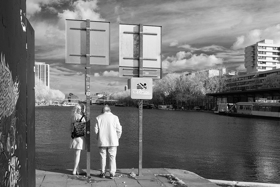 Infrared Photo of Woman and Man Looking at an Urban Waterway.